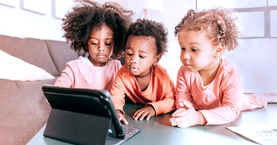 An image of a group of three kids looking at a tablet.