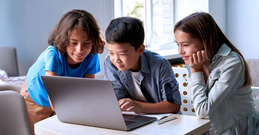 Three school kids watching virtual lab simulations on a laptop.