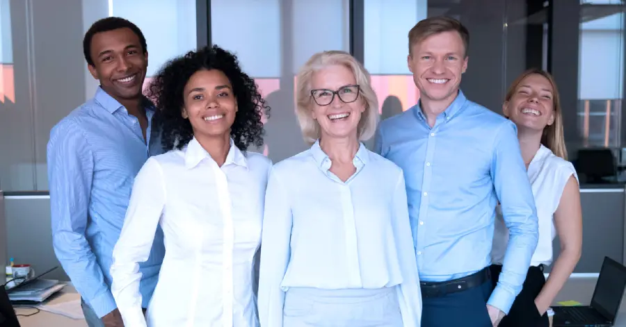  Diverse excited group of happy company employees standing posing for photo representing cross-generational workforce.