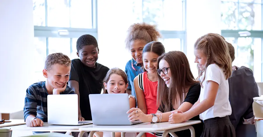 A group of multiracial students learning with their teacher on a laptop about how to ensure security & privacy in Learning Platforms.