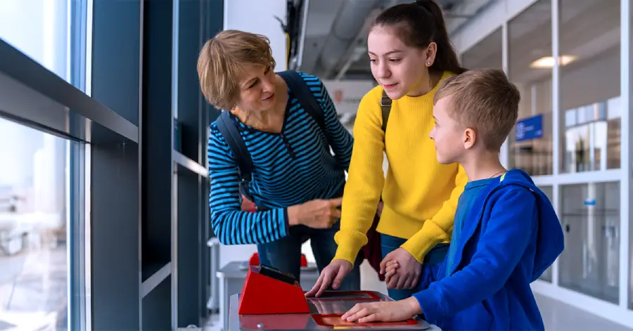 A teenage girl and a little boy learning about electromagnetic induction while interacting with a display with their teacher.