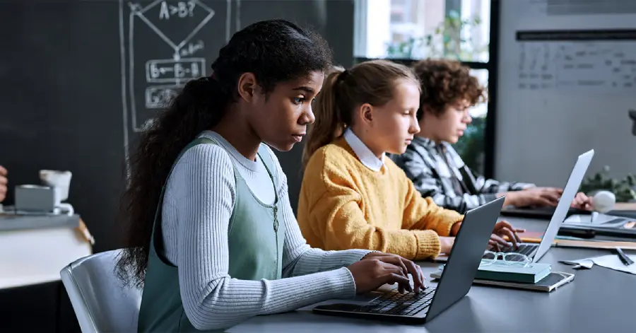 A group of students sitting with their laptops and learning security & privacy in Learning Platforms.