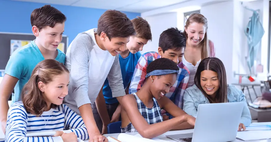 A multi-racial group of students with a laptop learning about outsourcing learning content development 