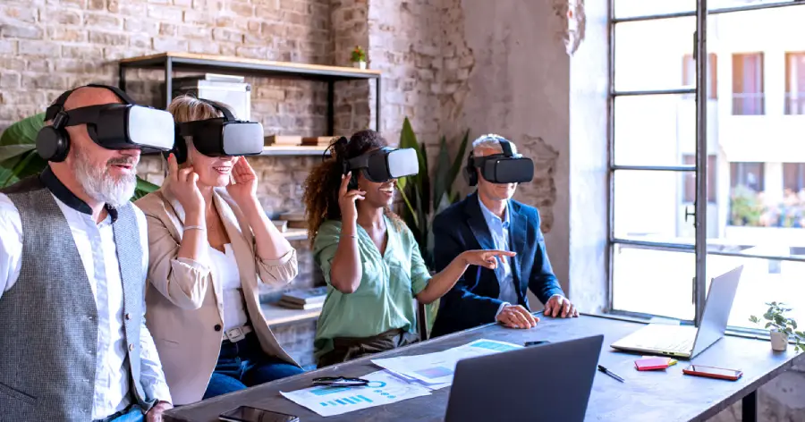 A multiracial group learning through VR simulation with a VR headset about the custom content development trends for corporate learning. 