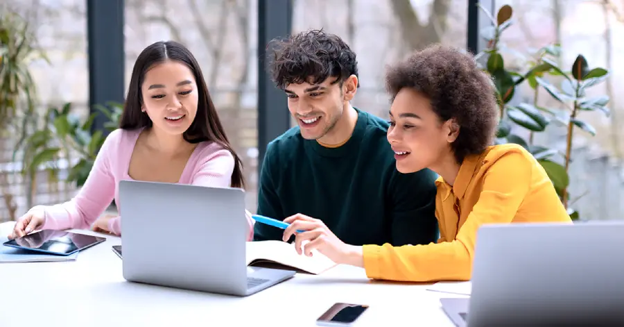 Three higher-ed students, one male and two females learning on a laptop about content refresh.