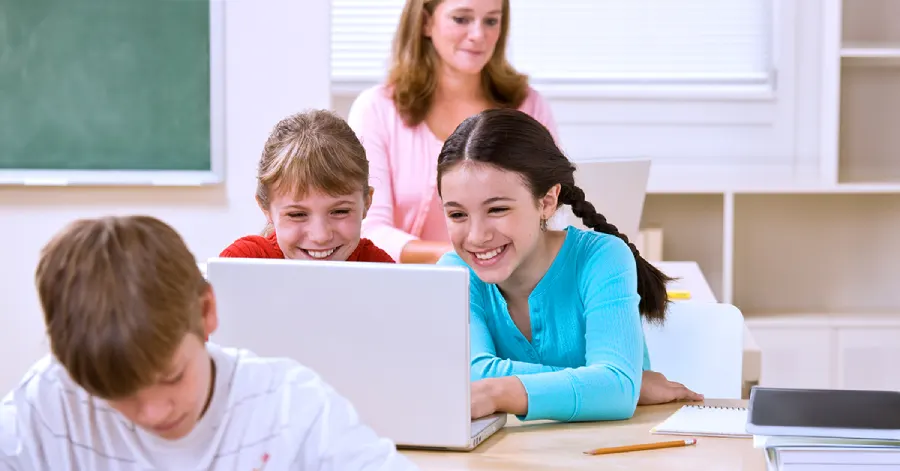 Two young girls with a laptop learning about content migration.