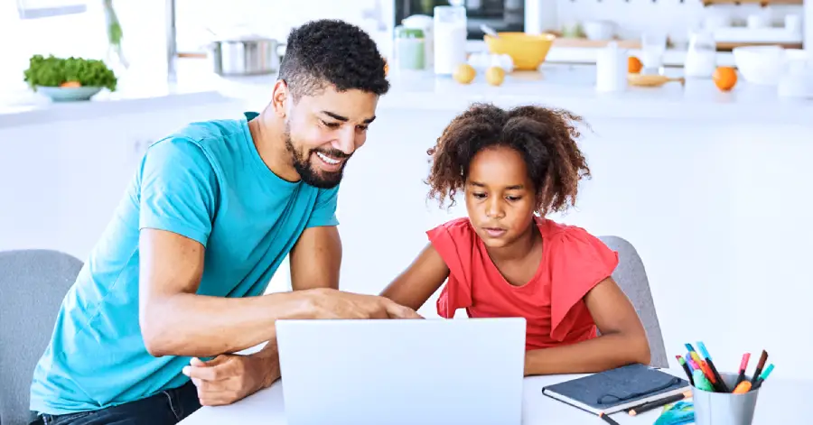  An image featuring a father and a daughter sitting with a laptop. 