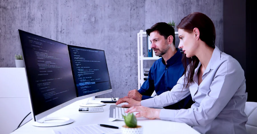 A group of male and female developer sitting together and working on their laptops 